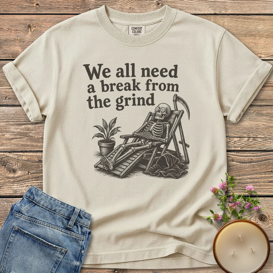 A Break From the Grind t-shirt, a skeleton relaxing in a beach chair with a houseplant under We all need a break from the grind, on an Ivory Comfort Colors tee