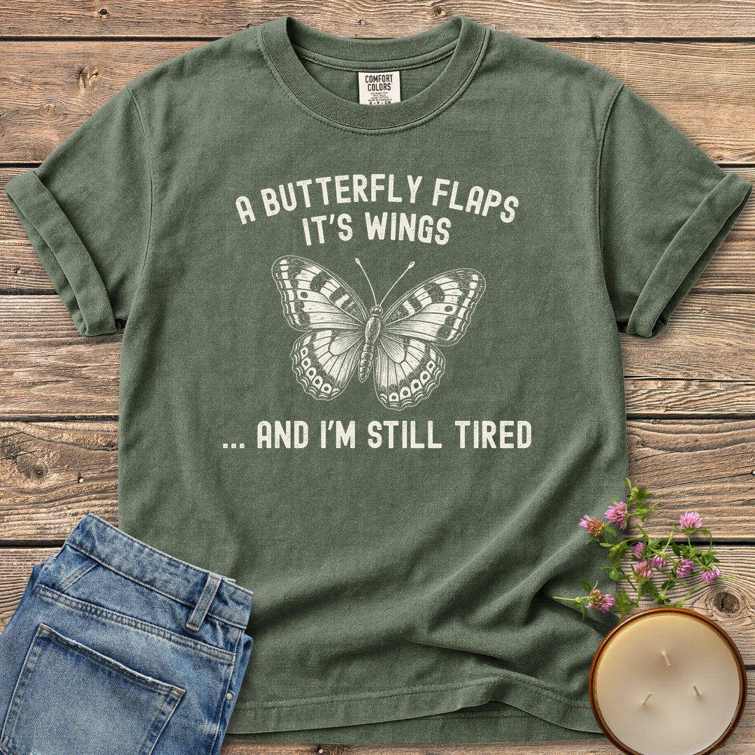 And I'm Still Tired t-shirt, a detailed butterfly between A Butterfly Flaps It's Wings and ... And I'm Still Tired, on a Moss Comfort Colors tee