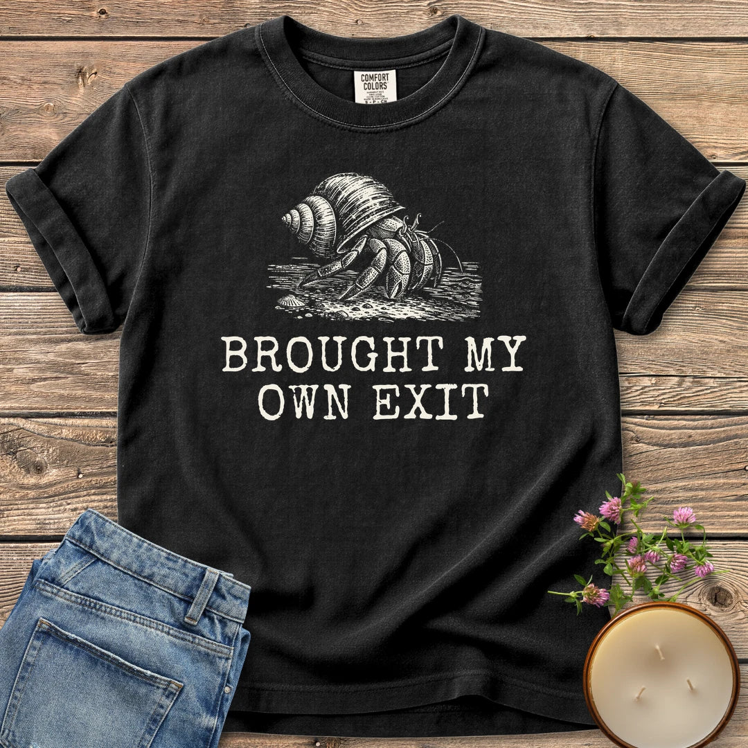 Brought My Own Exit t-shirt, a hermit crab carrying its shell above Brought My Own Exit, on a Black Comfort Colors tee