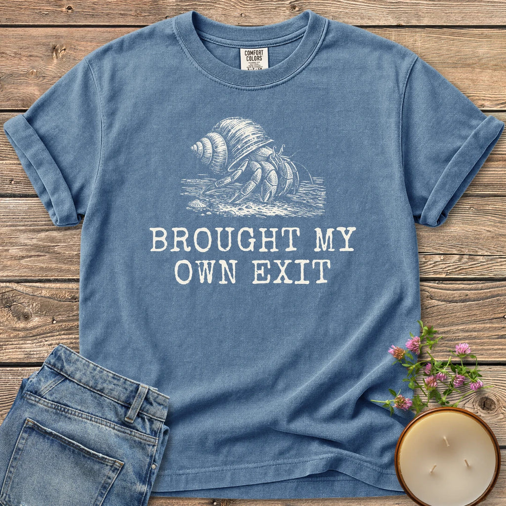 Brought My Own Exit t-shirt, a hermit crab carrying its shell above Brought My Own Exit, on a Blue Jean Comfort Colors tee