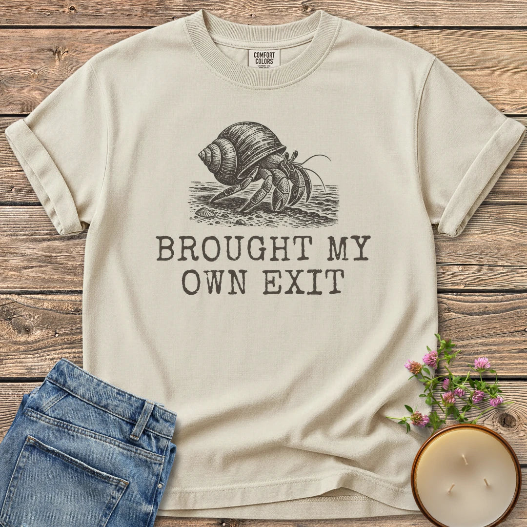 Brought My Own Exit t-shirt, a hermit crab carrying its shell above Brought My Own Exit, on an Ivory Comfort Colors tee