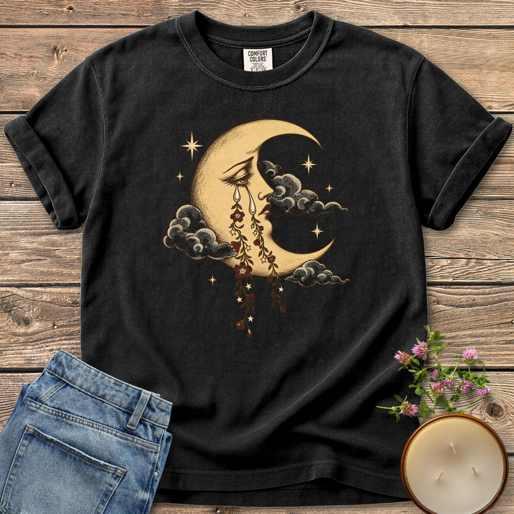 Crescent Moon Floral Tears t-shirt, a crescent moon crying tears of hanging flowers among clouds and stars, on a Black Comfort Colors tee
