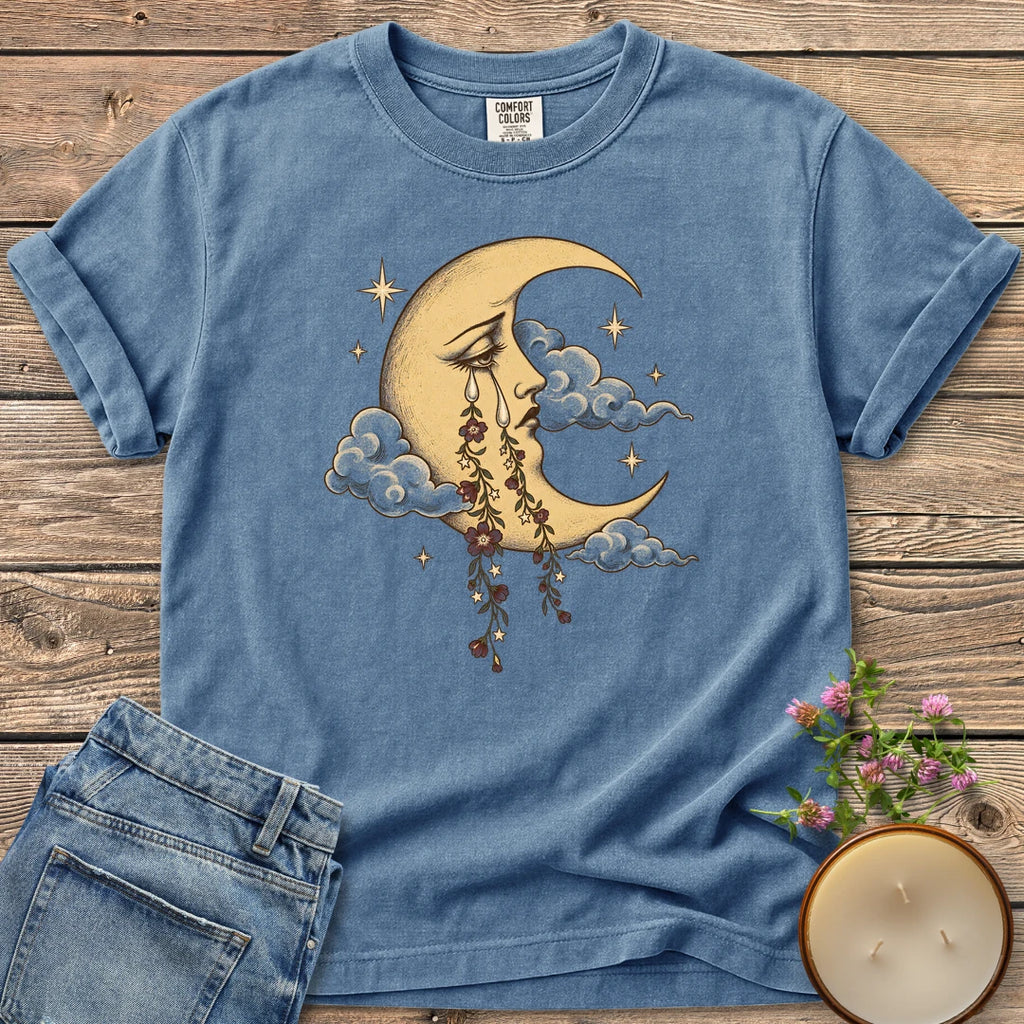 Crescent Moon Floral Tears t-shirt, a crescent moon crying tears of hanging flowers among clouds and stars, on a Blue Jean Comfort Colors tee