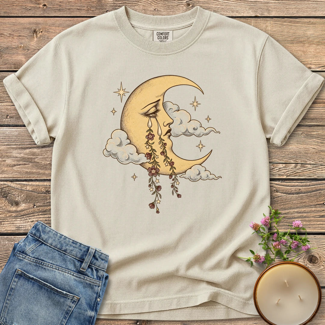 Crescent Moon Floral Tears t-shirt, a crescent moon crying tears of hanging flowers among clouds and stars, on an Ivory Comfort Colors tee
