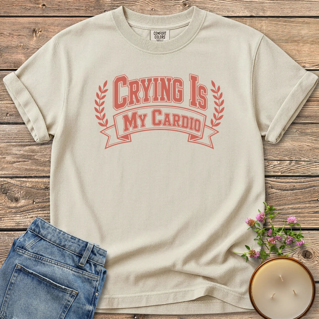 Crying Is My Cardio t-shirt, Crying Is My Cardio in varsity letters on a banner with laurel branches, on an Ivory Comfort Colors tee