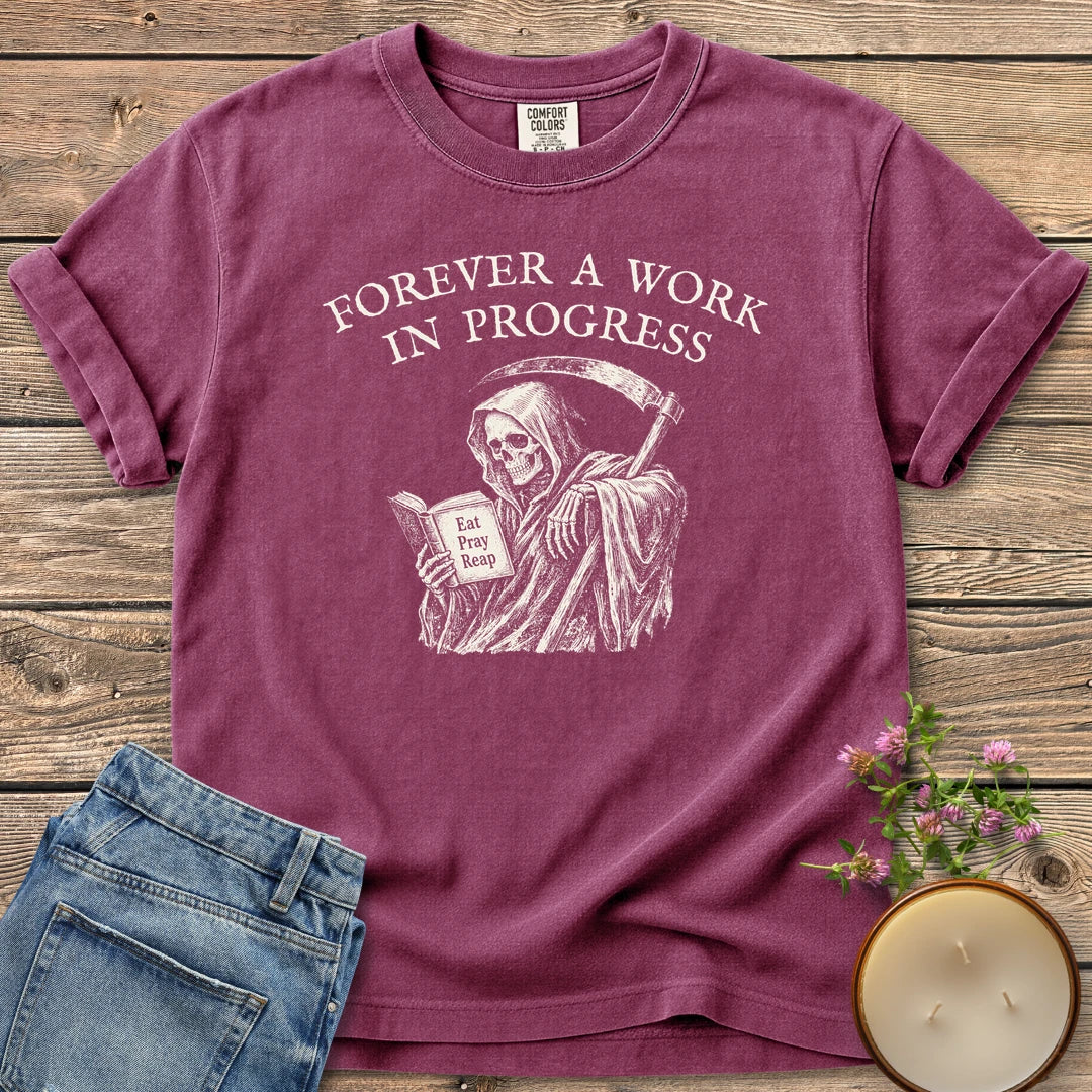 Eat Pray Reap t-shirt, a grim reaper reading a book titled Eat Pray Reap under Forever A Work In Progress, on a Berry Comfort Colors tee