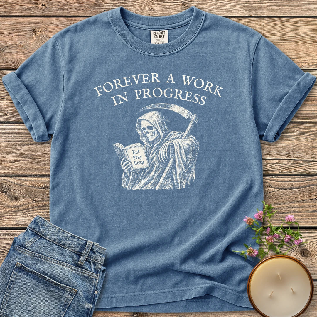 Eat Pray Reap t-shirt, a grim reaper reading a book titled Eat Pray Reap under Forever A Work In Progress, on a Blue Jean Comfort Colors tee