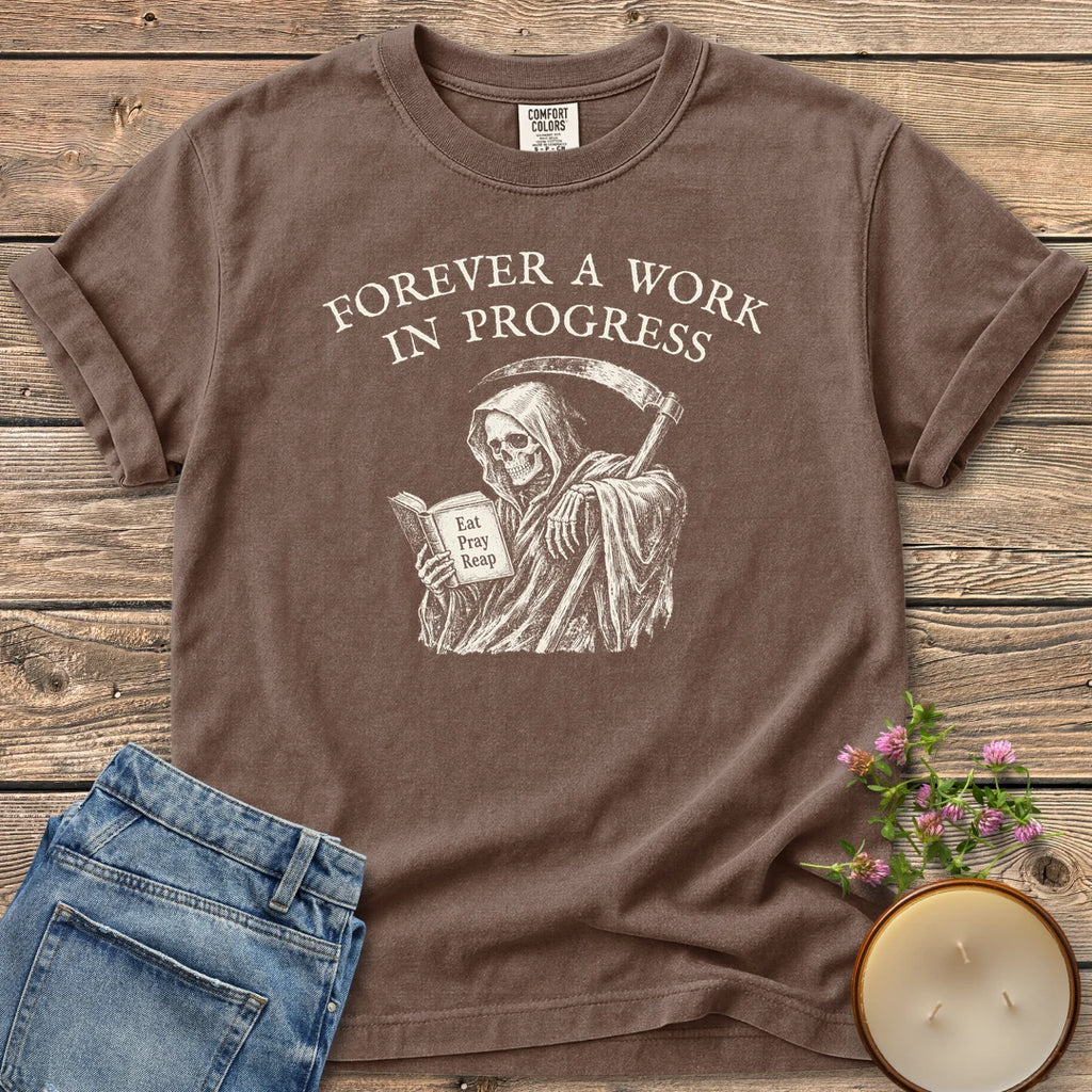 Eat Pray Reap t-shirt, a grim reaper reading a book titled Eat Pray Reap under Forever A Work In Progress, on an Espresso Comfort Colors tee