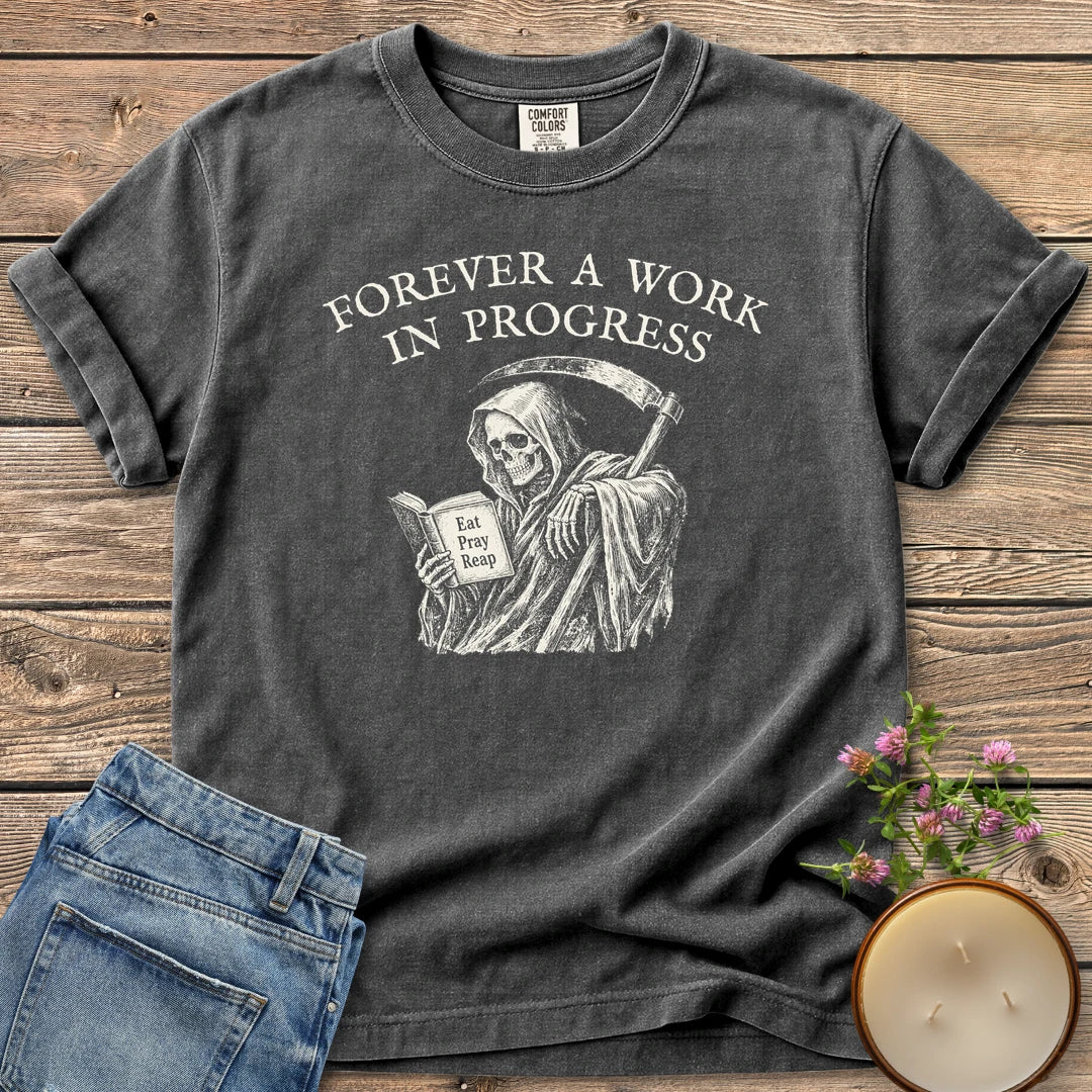 Eat Pray Reap t-shirt, a grim reaper reading a book titled Eat Pray Reap under Forever A Work In Progress, on a Pepper Comfort Colors tee