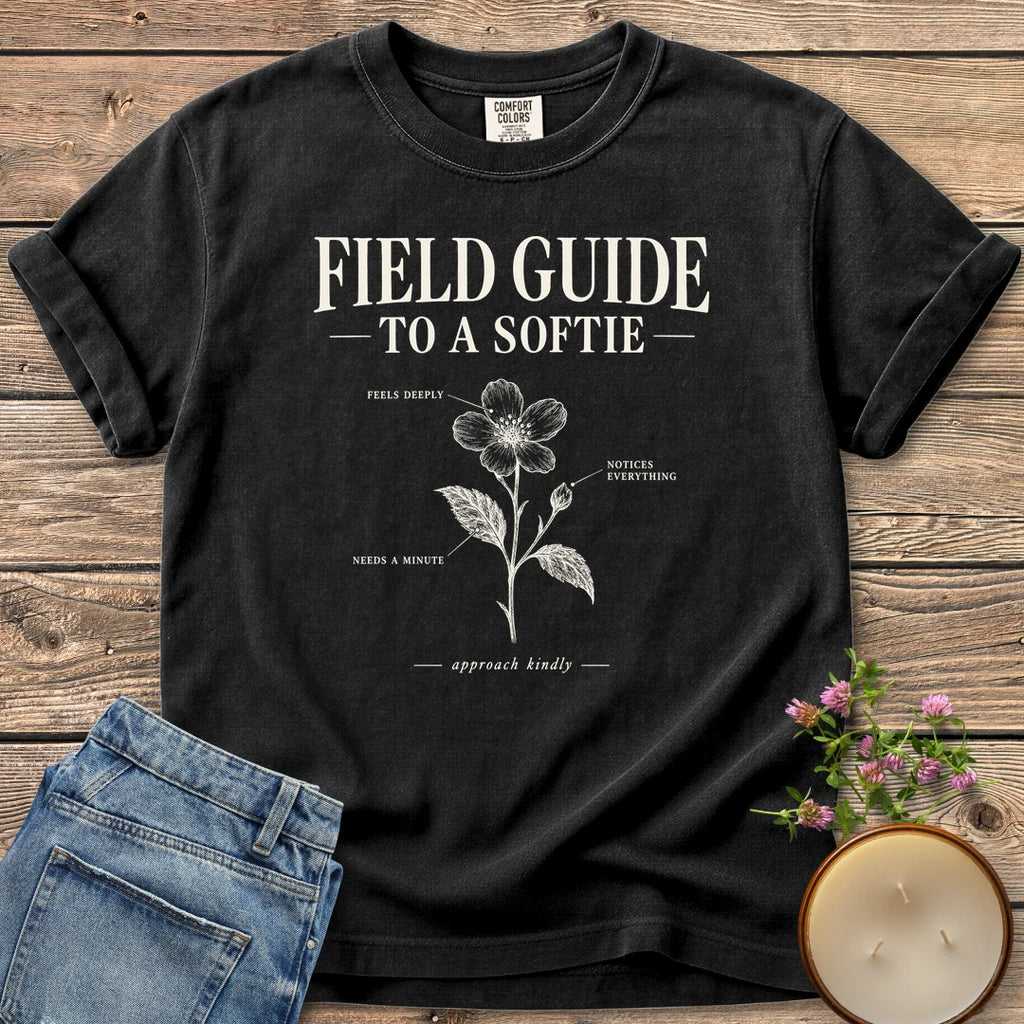 Field Guide To A Softie t-shirt, Field Guide To A Softie with a labeled flower reading feels deeply, notices everything, needs a minute, on a Black Comfort Colors tee