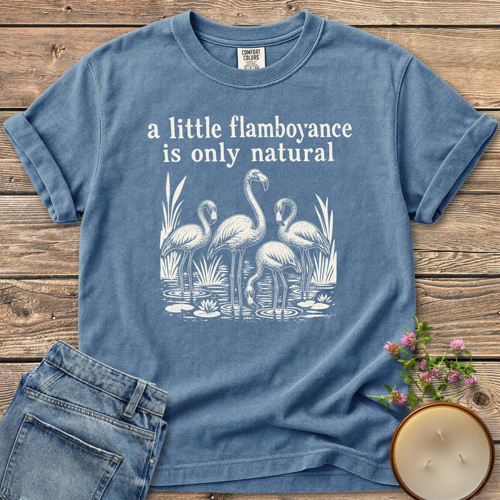 Flamboyance Is Only Natural t-shirt, a group of flamingos wading in a pond under a little flamboyance is only natural, on a Blue Jean Comfort Colors tee