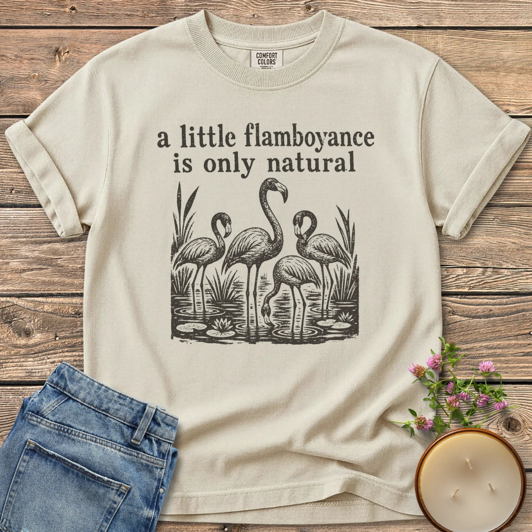 Flamboyance Is Only Natural t-shirt, a group of flamingos wading in a pond under a little flamboyance is only natural, on an Ivory Comfort Colors tee