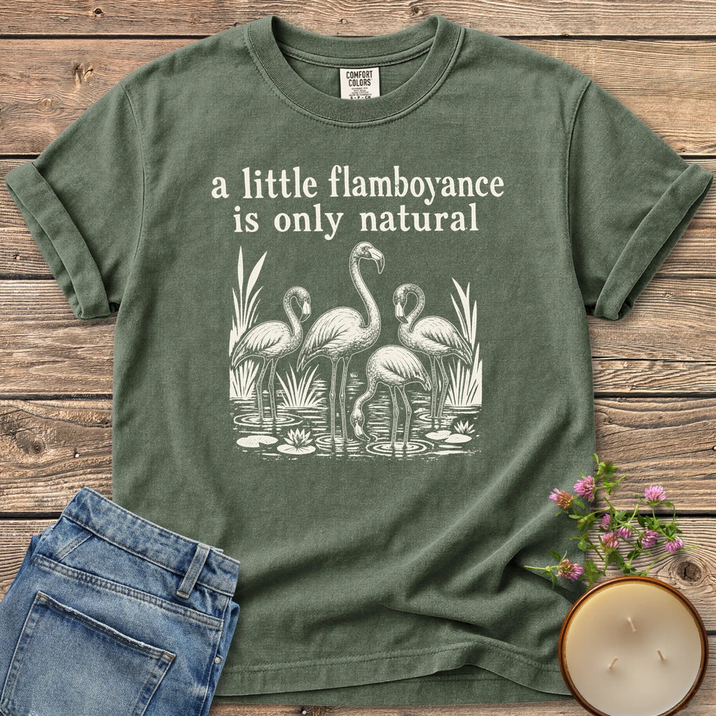 Flamboyance Is Only Natural t-shirt, a group of flamingos wading in a pond under a little flamboyance is only natural, on a Moss Comfort Colors tee