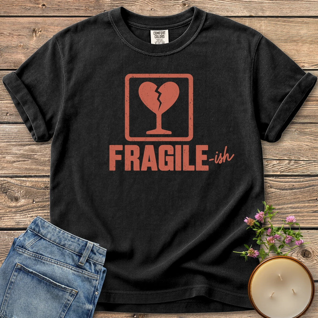 Fragile-ish t-shirt, a shipping label with a broken heart and cracked glass above Fragile-ish, on a Black Comfort Colors tee