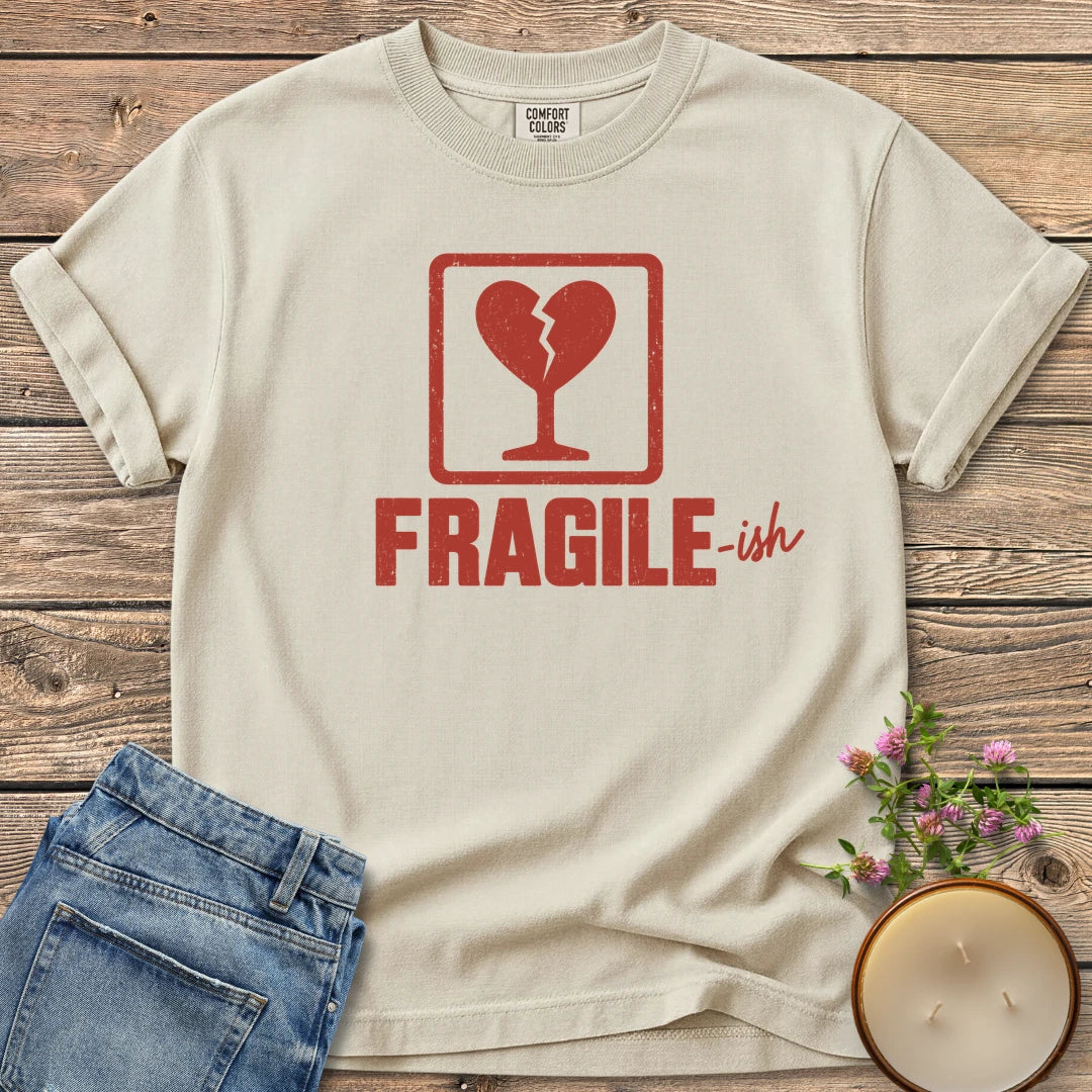 Fragile-ish t-shirt, a shipping label with a broken heart and cracked glass above Fragile-ish, on an Ivory Comfort Colors tee