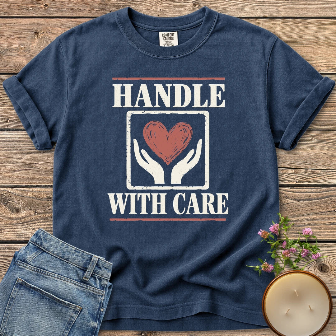Handle With Care t-shirt, Handle With Care around two hands holding a heart, on a Navy Comfort Colors tee