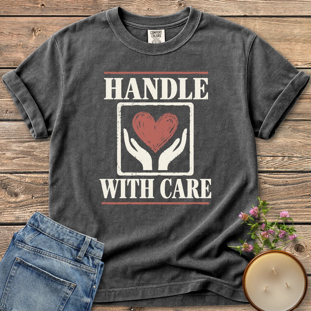 Handle With Care t-shirt, Handle With Care around two hands holding a heart, on a Pepper Comfort Colors tee