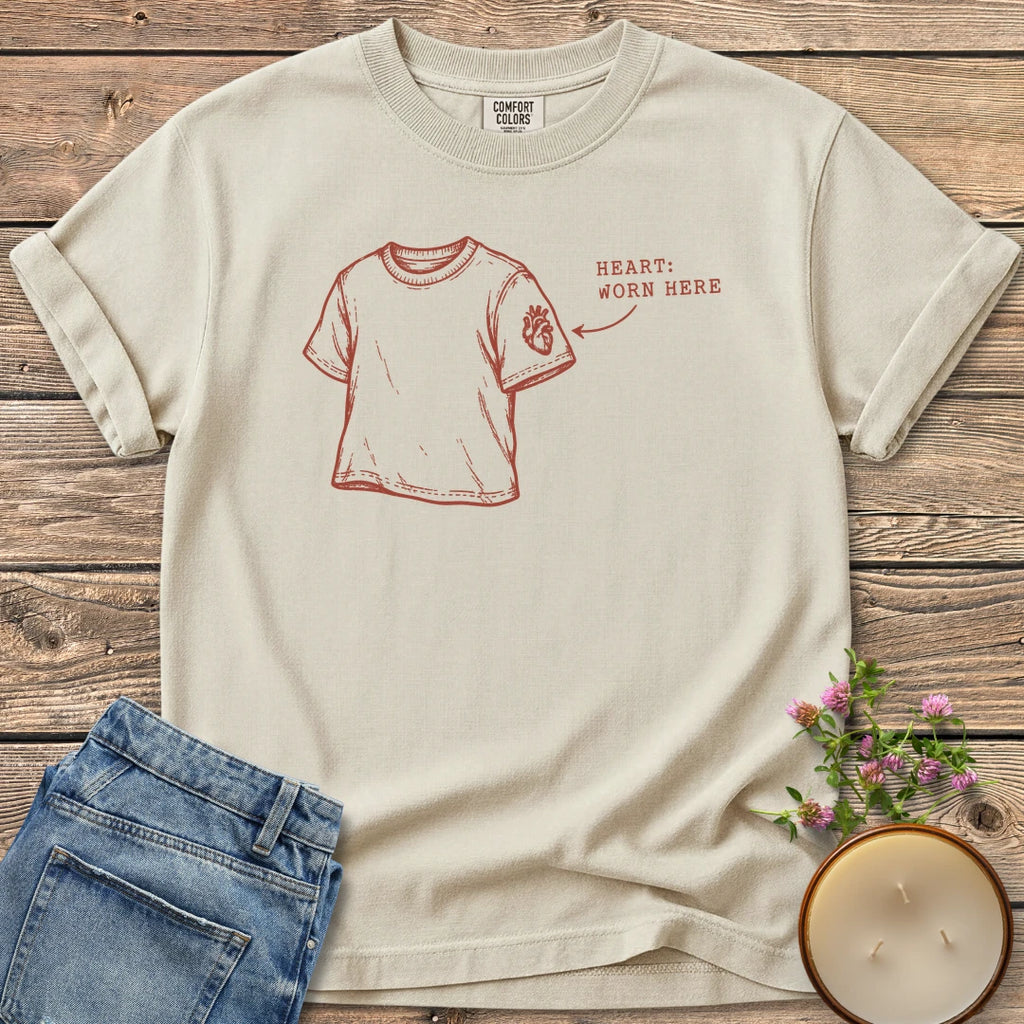 Heart Worn Here t-shirt, a sketched t-shirt with an anatomical heart on the sleeve and Heart: Worn Here, on an Ivory Comfort Colors tee