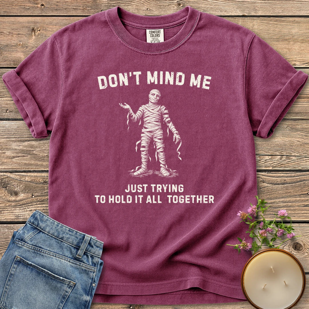 Hold It All Together t-shirt, a mummy with unraveling bandages between Don't Mind Me and Just Trying To Hold It All Together, on a Berry Comfort Colors tee