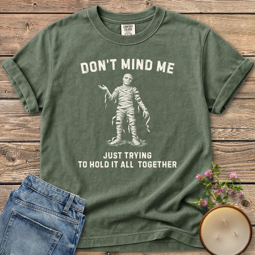 Hold It All Together t-shirt, a mummy with unraveling bandages between Don't Mind Me and Just Trying To Hold It All Together, on a Moss Comfort Colors tee