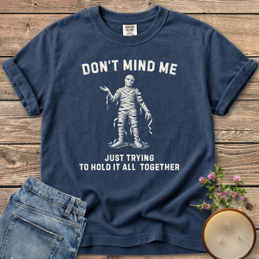 Hold It All Together t-shirt, a mummy with unraveling bandages between Don't Mind Me and Just Trying To Hold It All Together, on a Navy Comfort Colors tee