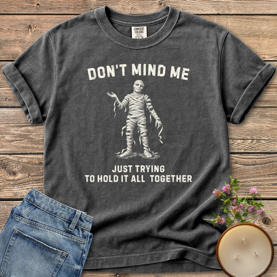 Hold It All Together t-shirt, a mummy with unraveling bandages between Don't Mind Me and Just Trying To Hold It All Together, on a Pepper Comfort Colors tee