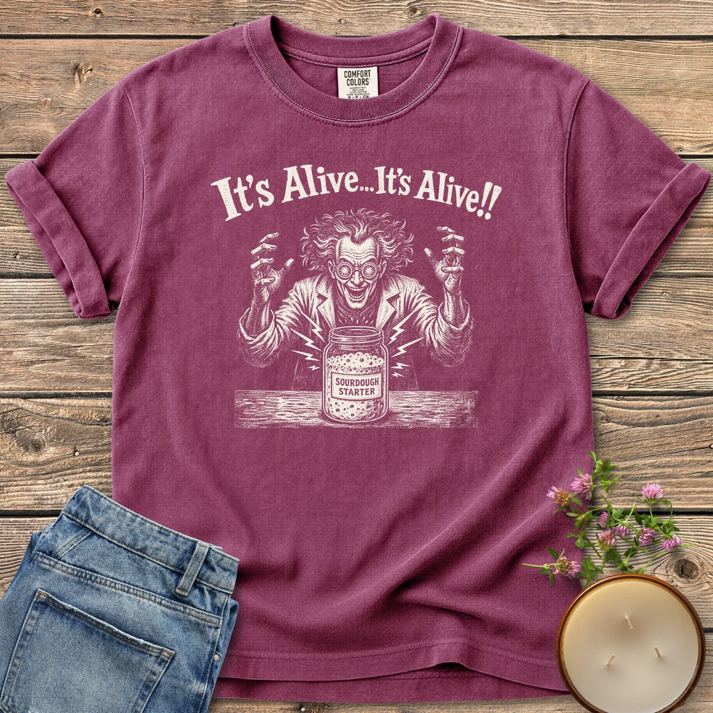 It's Alive t-shirt, a mad scientist celebrating a bubbling sourdough starter jar under It's Alive... It's Alive!!, on a Berry Comfort Colors tee