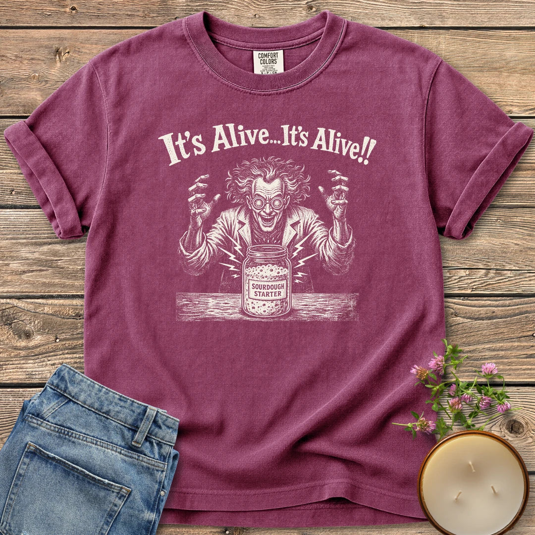 It's Alive t-shirt, a mad scientist celebrating a bubbling sourdough starter jar under It's Alive... It's Alive!!, on a Berry Comfort Colors tee
