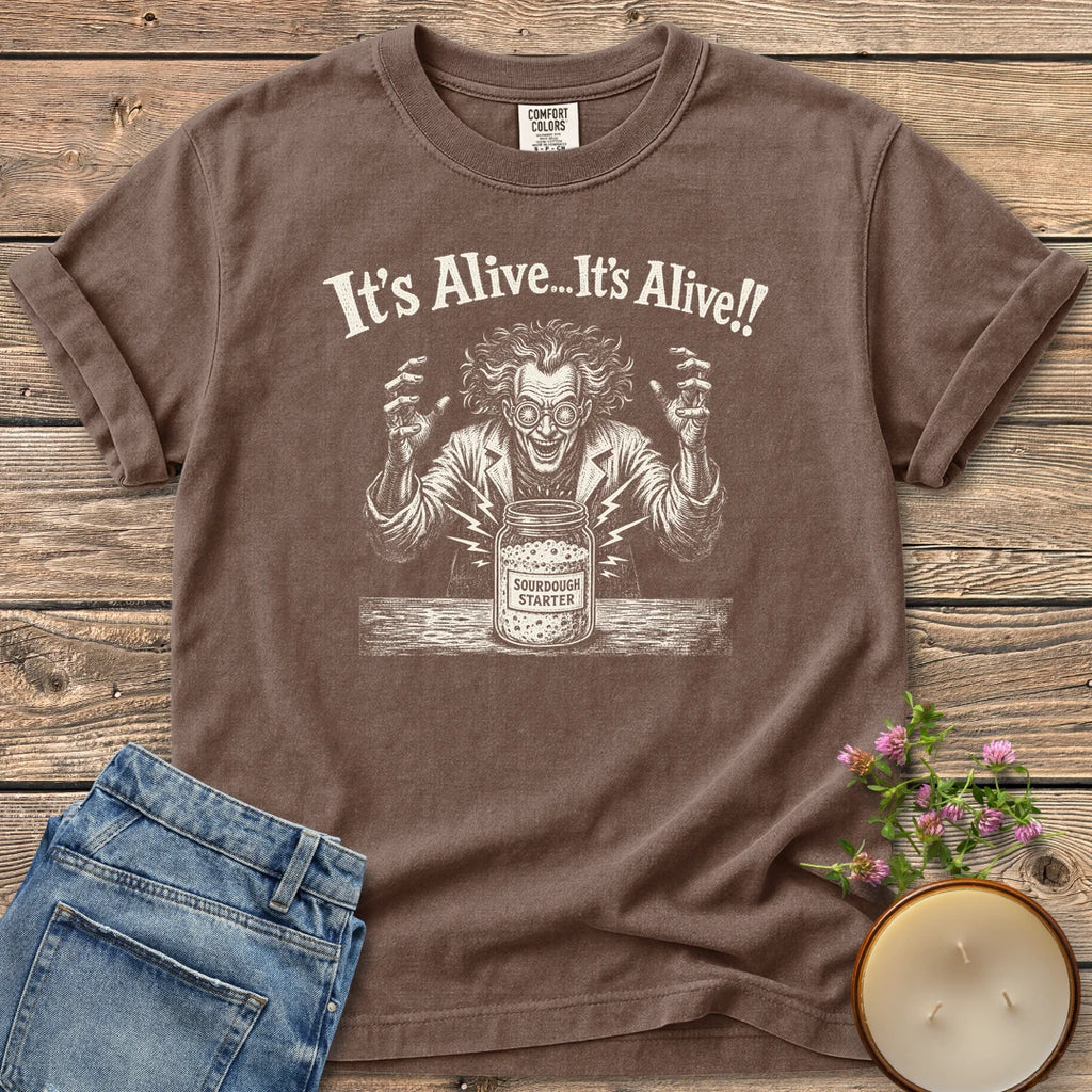 It's Alive t-shirt, a mad scientist celebrating a bubbling sourdough starter jar under It's Alive... It's Alive!!, on an Espresso Comfort Colors tee