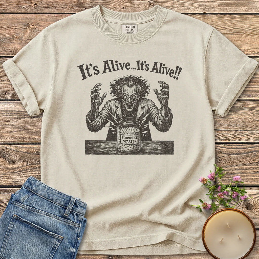 It's Alive t-shirt, a mad scientist celebrating a bubbling sourdough starter jar under It's Alive... It's Alive!!, on an Ivory Comfort Colors tee