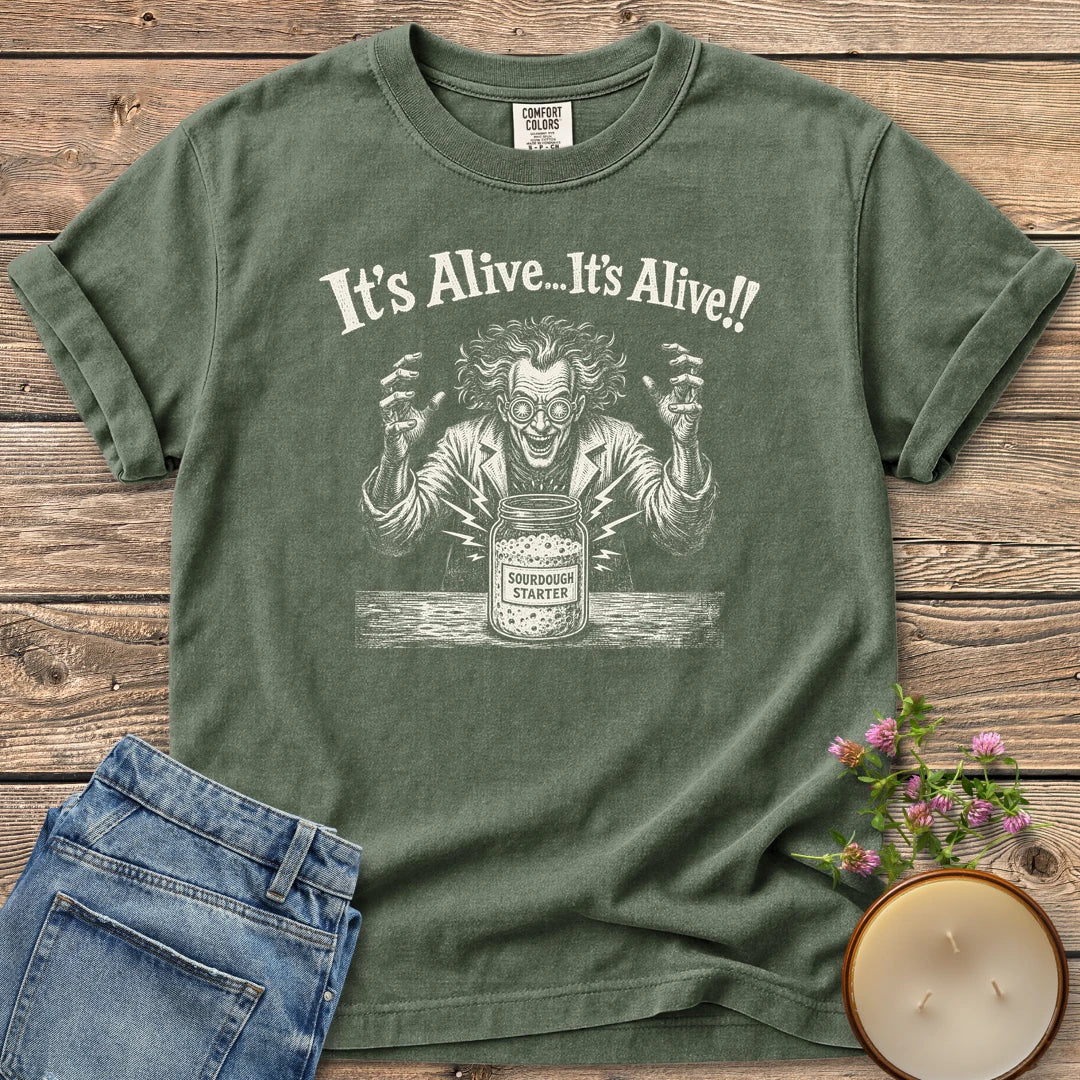 It's Alive t-shirt, a mad scientist celebrating a bubbling sourdough starter jar under It's Alive... It's Alive!!, on a Moss Comfort Colors tee