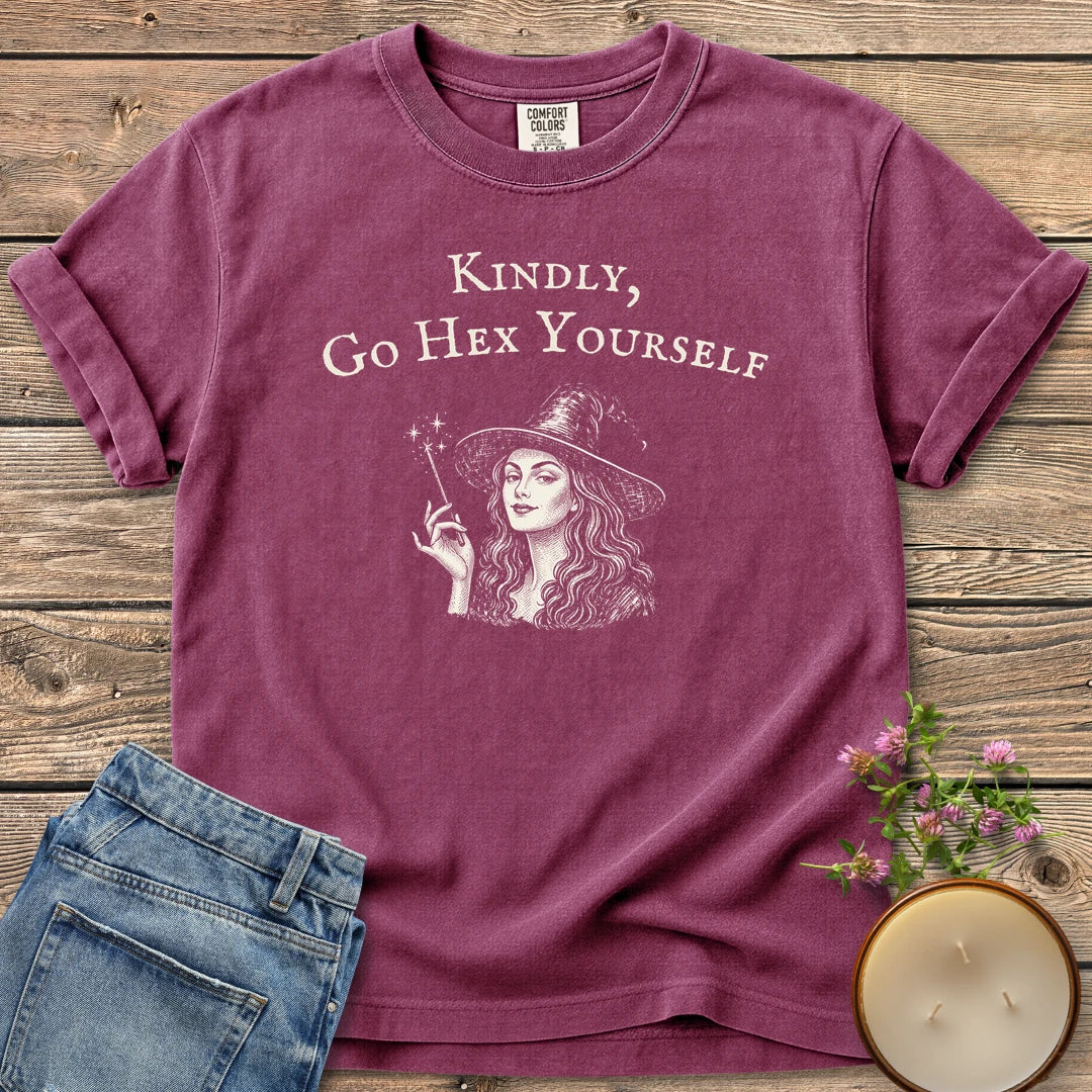 Kindly Go Hex Yourself t-shirt, a smiling witch with a wand under Kindly, Go Hex Yourself, on a Berry Comfort Colors tee