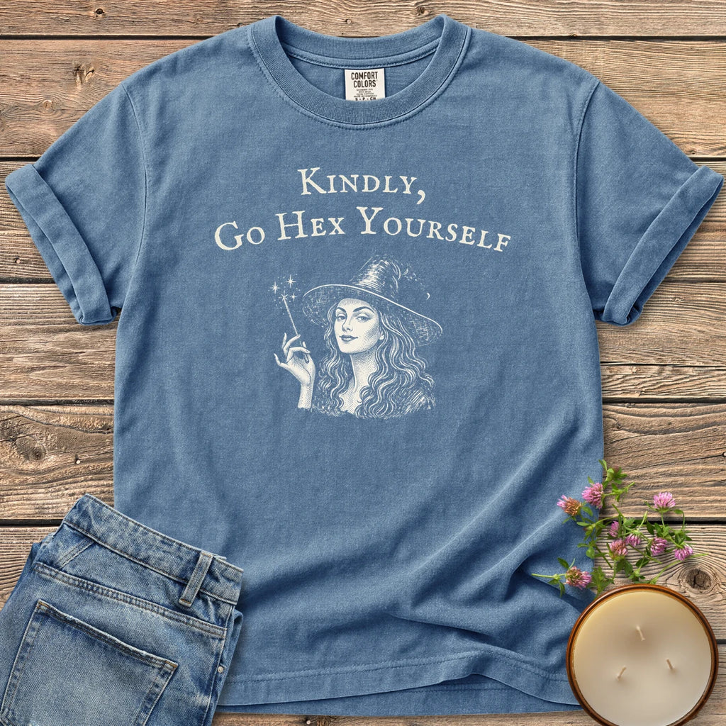 Kindly Go Hex Yourself t-shirt, a smiling witch with a wand under Kindly, Go Hex Yourself, on a Blue Jean Comfort Colors tee