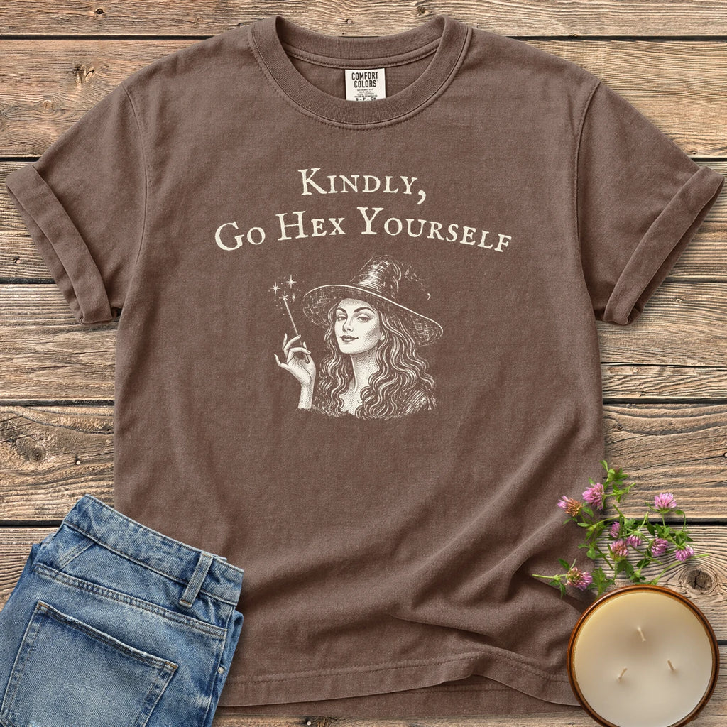 Kindly Go Hex Yourself t-shirt, a smiling witch with a wand under Kindly, Go Hex Yourself, on an Espresso Comfort Colors tee