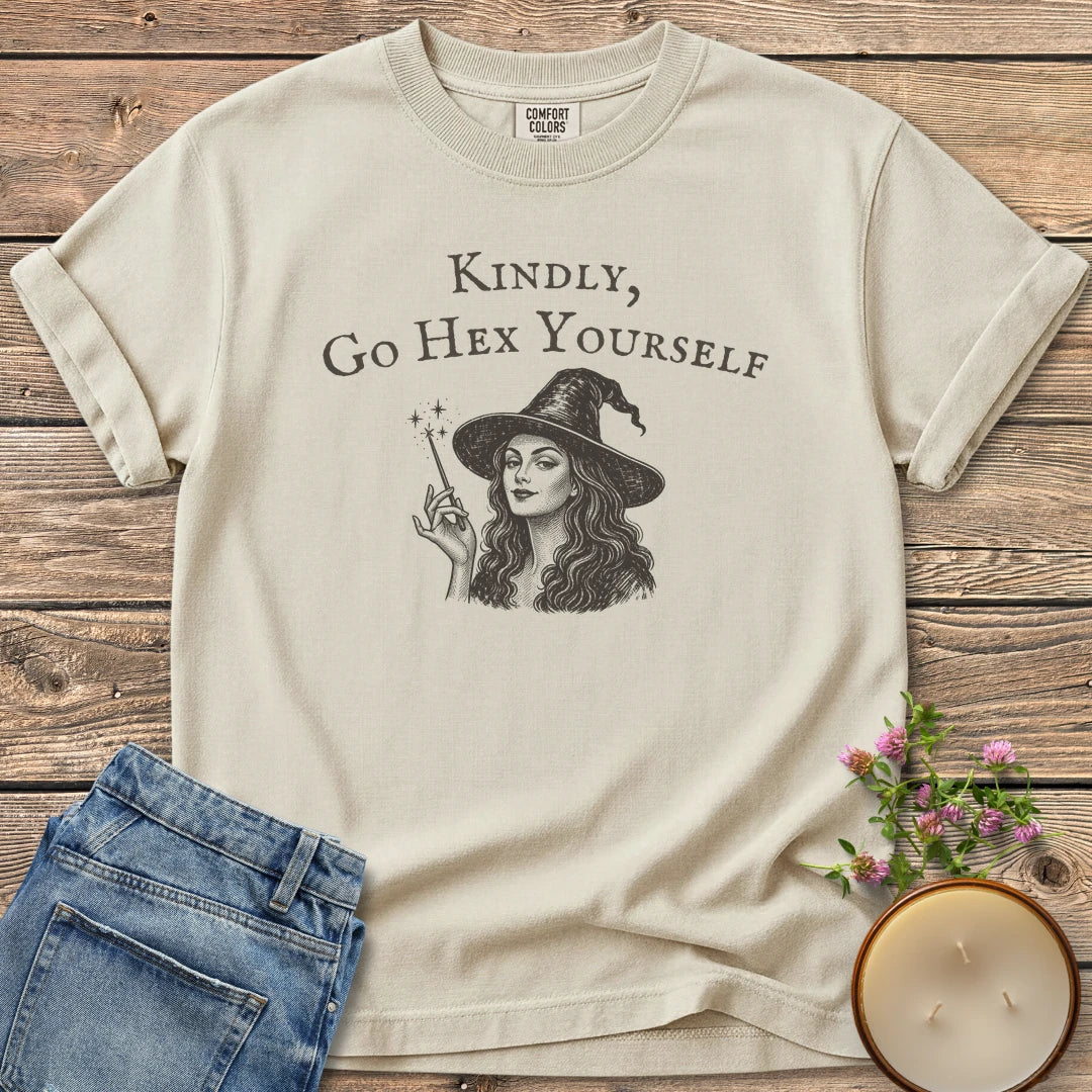 Kindly Go Hex Yourself t-shirt, a smiling witch with a wand under Kindly, Go Hex Yourself, on an Ivory Comfort Colors tee