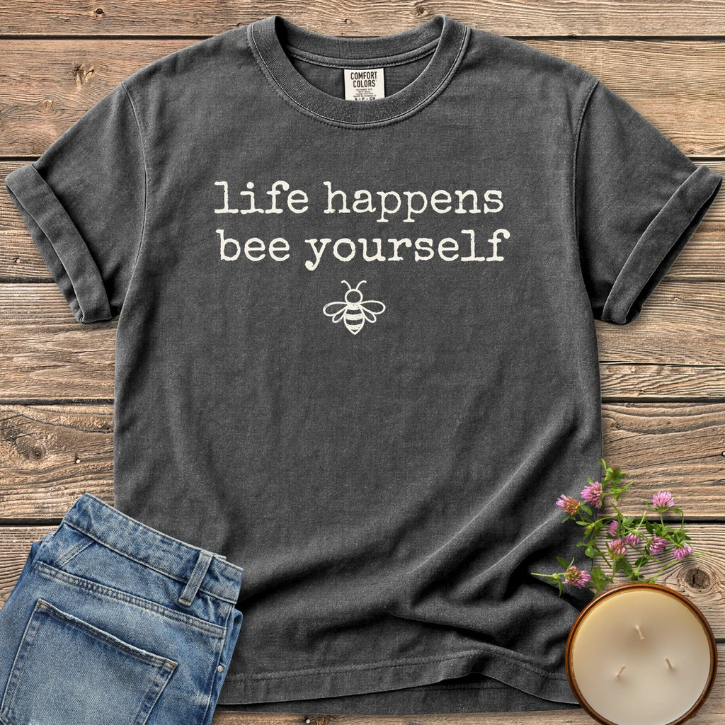 Life Happens Bee Yourself t-shirt, life happens bee yourself in typewriter type with a small bee, on a Pepper Comfort Colors tee