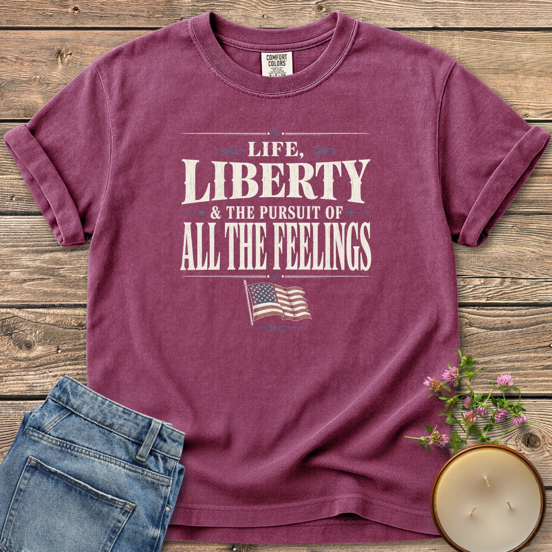 Life Liberty All the Feelings t-shirt, Life, Liberty & The Pursuit of All The Feelings in vintage type with a waving American flag, on a Berry Comfort Colors tee