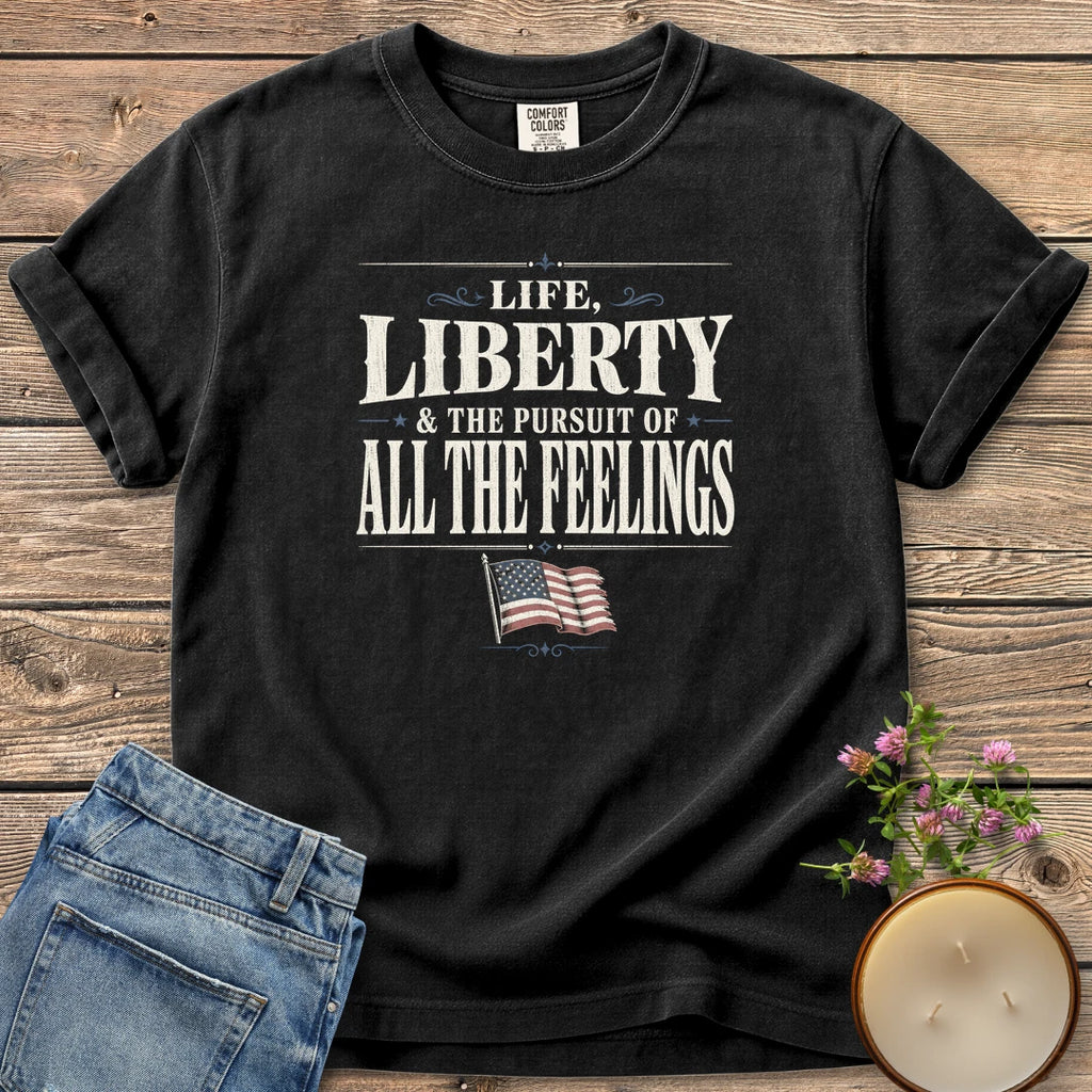 Life Liberty All the Feelings t-shirt, Life, Liberty & The Pursuit of All The Feelings in vintage type with a waving American flag, on a Black Comfort Colors tee