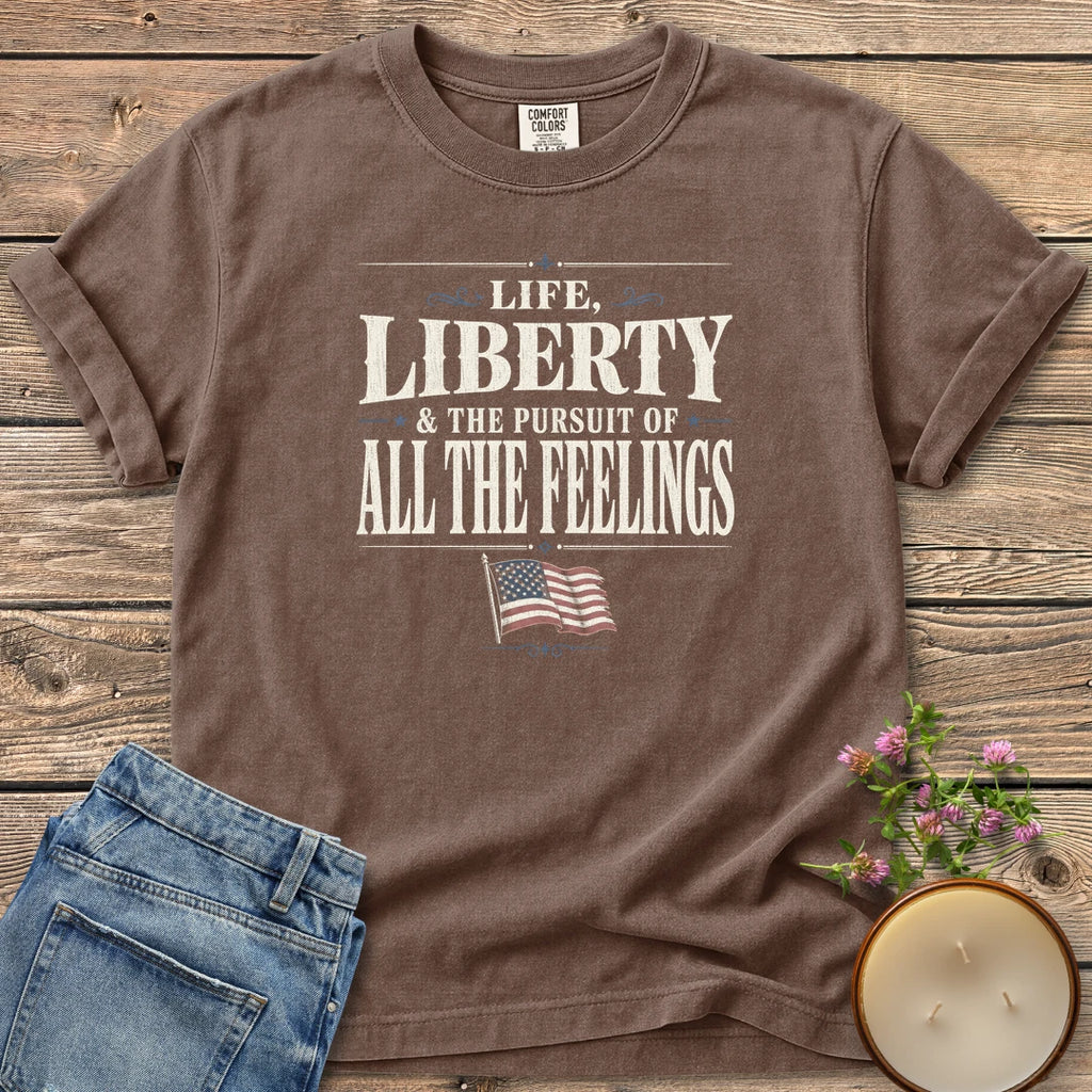Life Liberty All the Feelings t-shirt, Life, Liberty & The Pursuit of All The Feelings in vintage type with a waving American flag, on an Espresso Comfort Colors tee