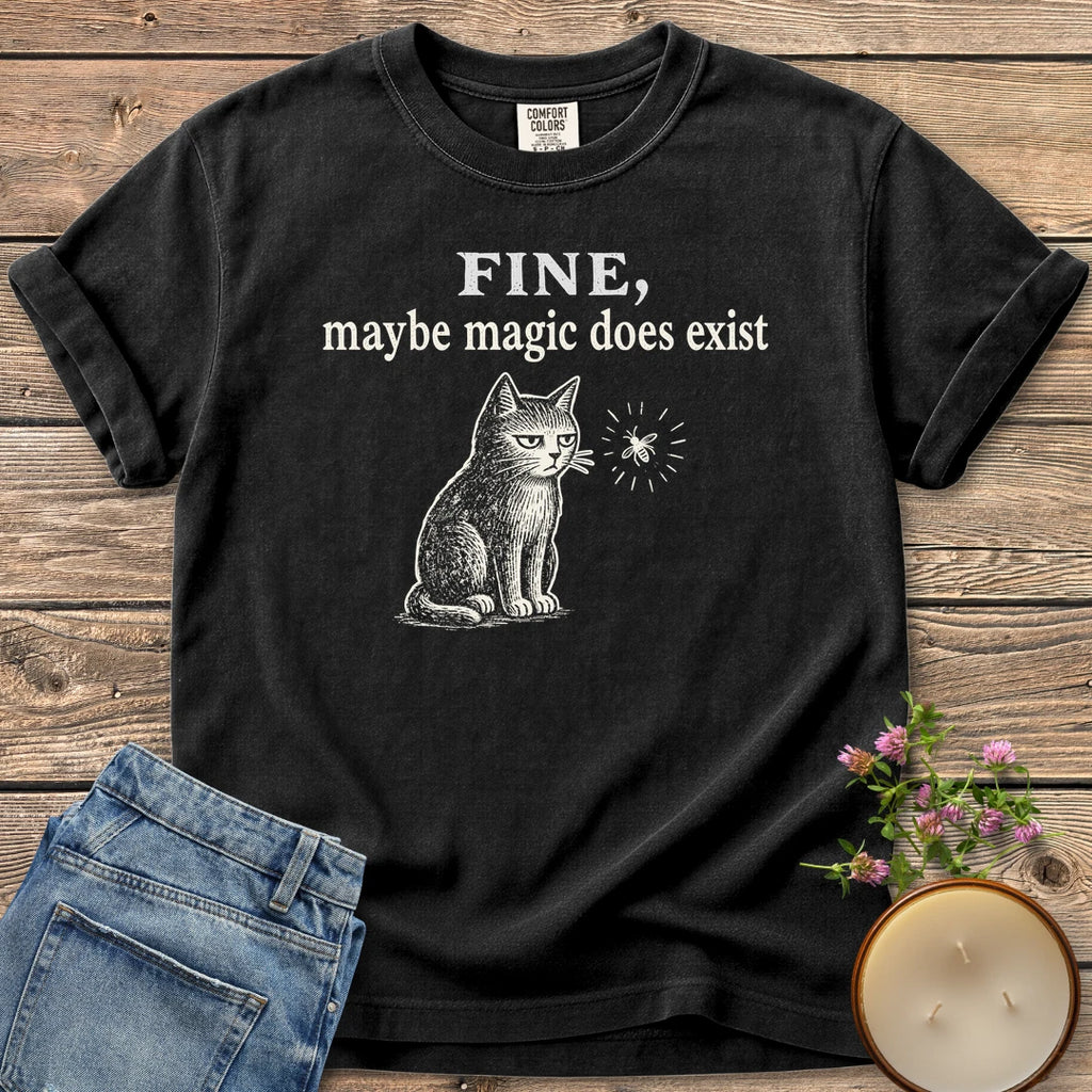 Maybe Magic Does Exist t-shirt, a grumpy cat watching a firefly under Fine, maybe magic does exist, on a Black Comfort Colors tee