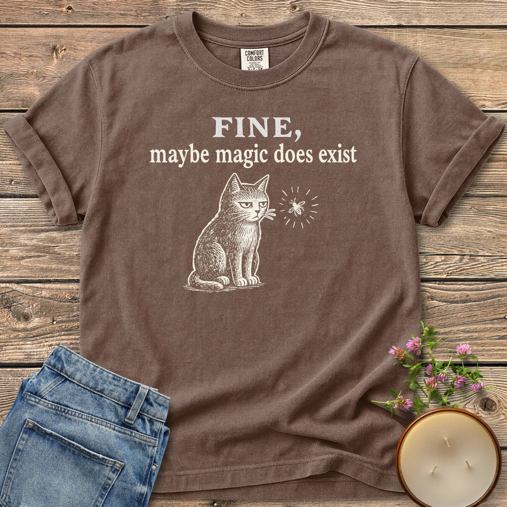Maybe Magic Does Exist t-shirt, a grumpy cat watching a firefly under Fine, maybe magic does exist, on an Espresso Comfort Colors tee