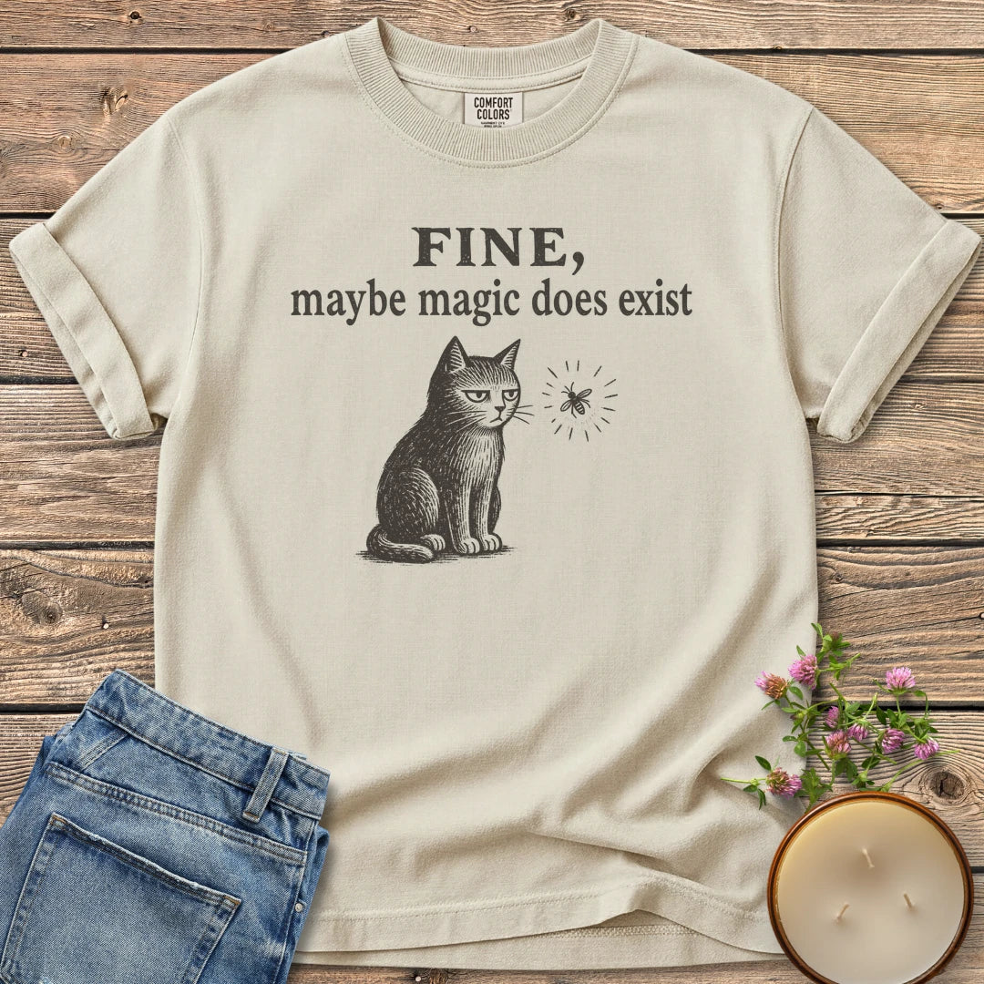 Maybe Magic Does Exist t-shirt, a grumpy cat watching a firefly under Fine, maybe magic does exist, on an Ivory Comfort Colors tee