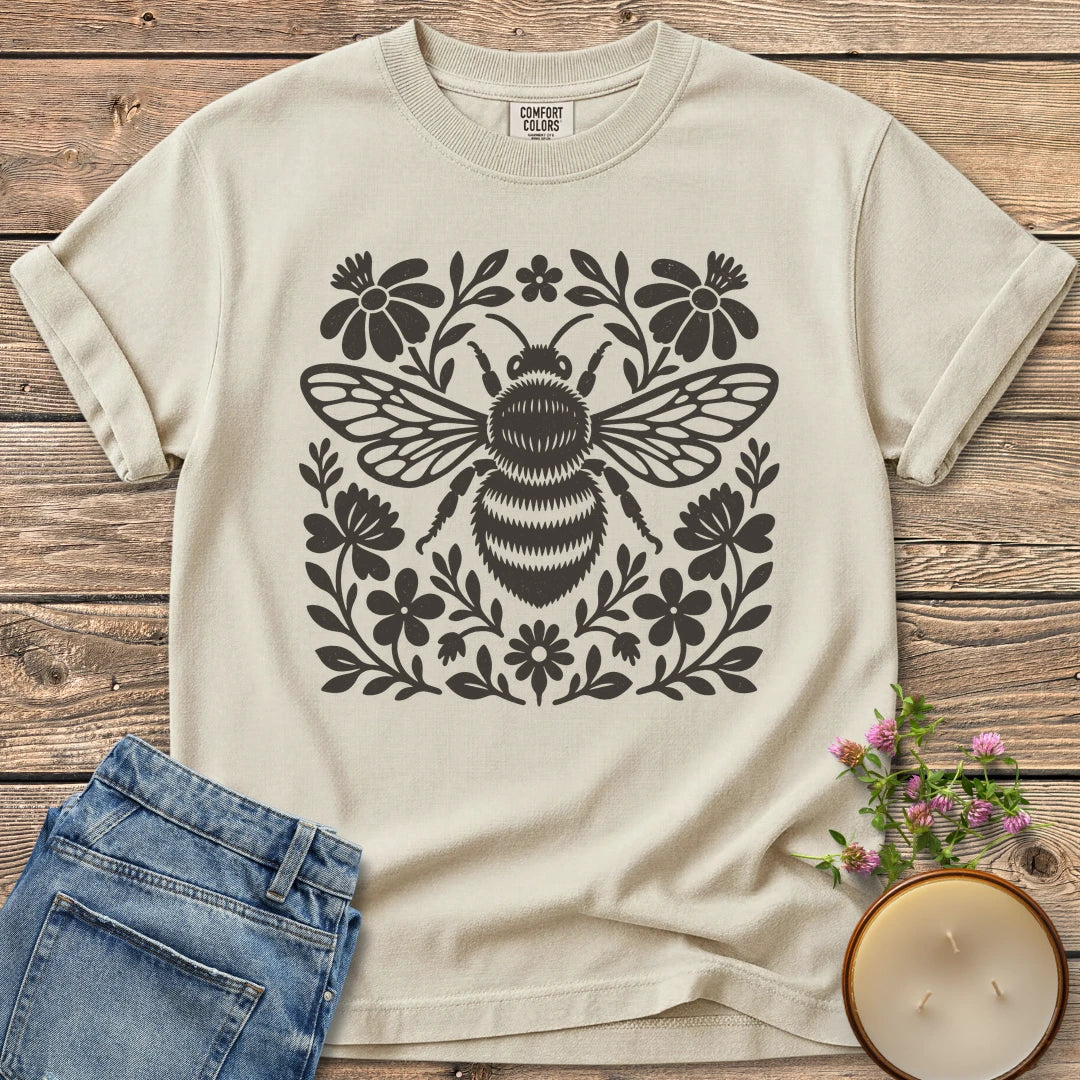 Meadow Bee Folk Art Flat t-shirt, a folk art bee surrounded by flat wildflowers, on an Ivory Comfort Colors tee