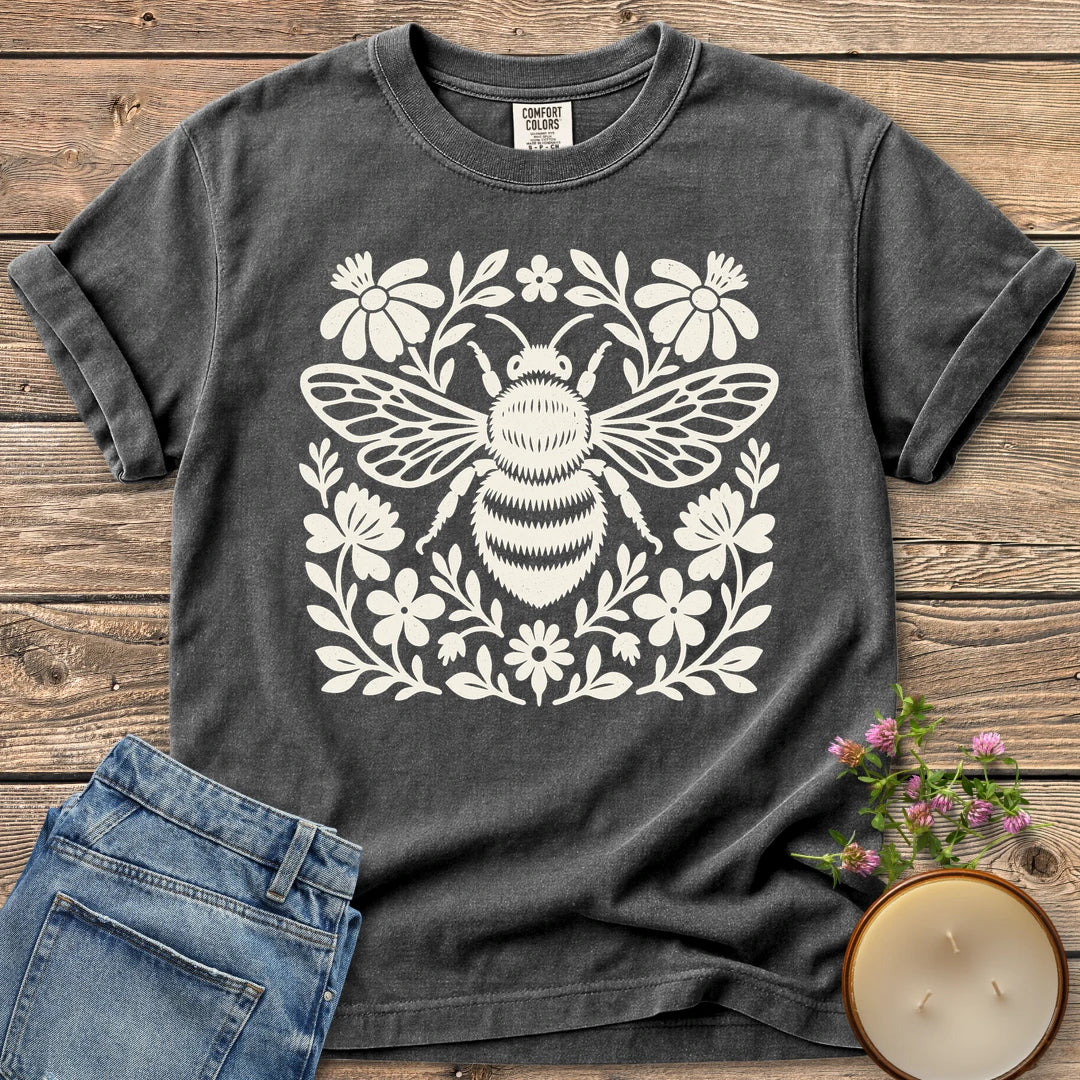 Meadow Bee Folk Art Flat t-shirt, a folk art bee surrounded by flat wildflowers, on a Pepper Comfort Colors tee