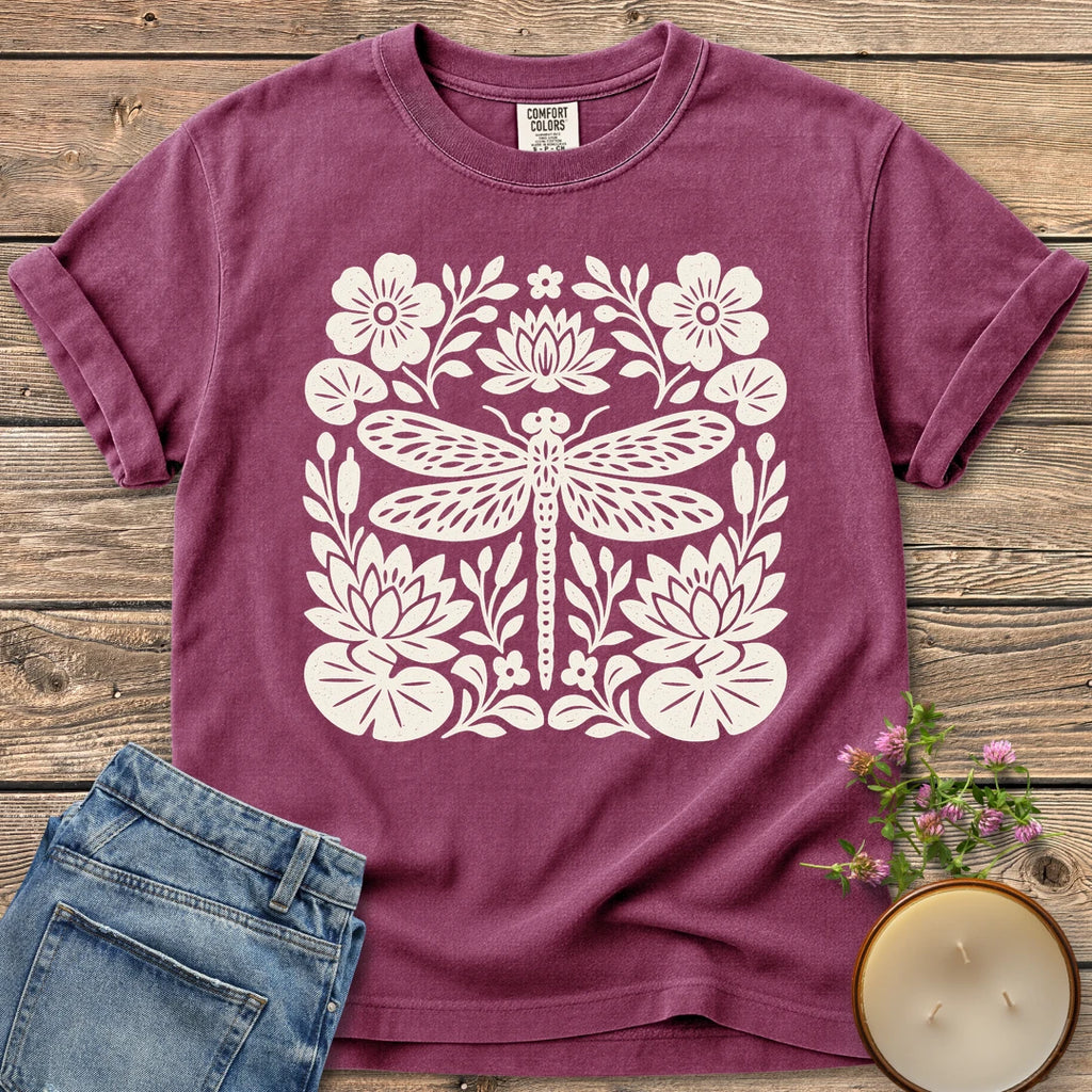 Meadow Dragonfly Folk Art Flat t-shirt, a folk art dragonfly surrounded by lily pads and flowers, on a Berry Comfort Colors tee