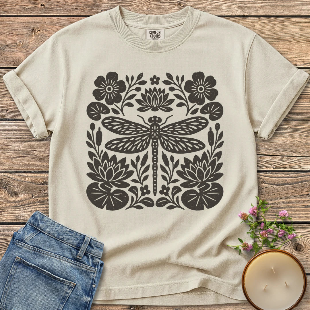 Meadow Dragonfly Folk Art Flat t-shirt, a folk art dragonfly surrounded by lily pads and flowers, on an Ivory Comfort Colors tee