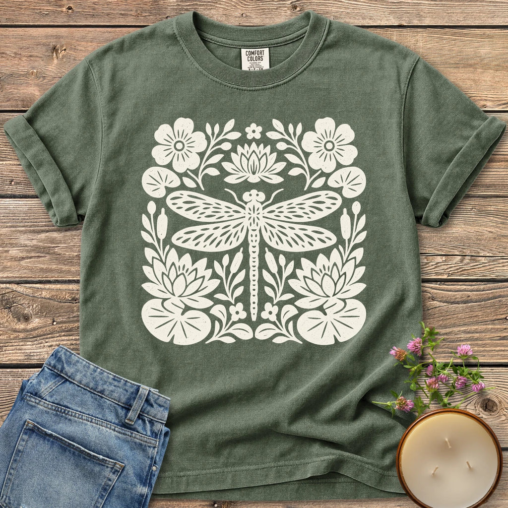 Meadow Dragonfly Folk Art Flat t-shirt, a folk art dragonfly surrounded by lily pads and flowers, on a Moss Comfort Colors tee