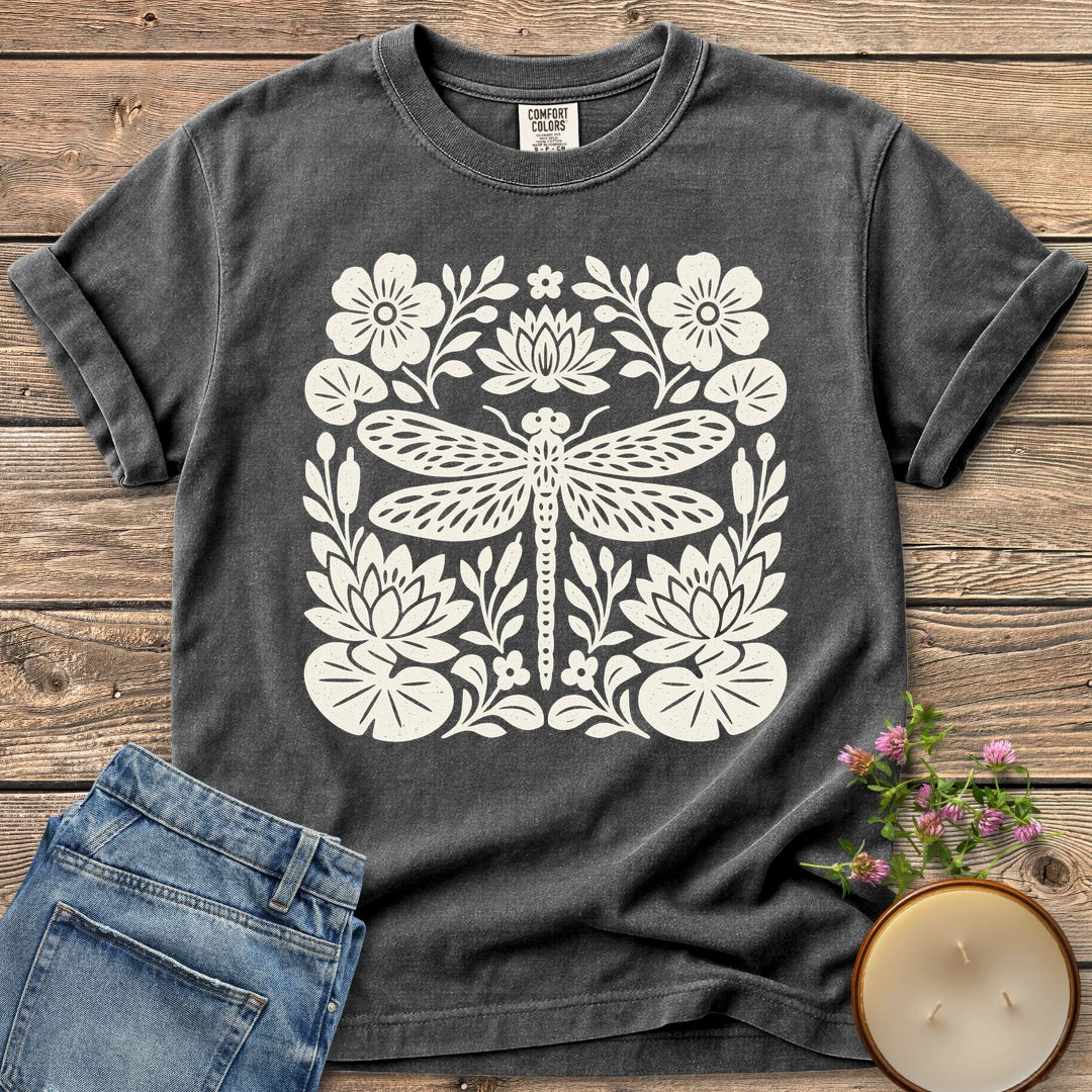 Meadow Dragonfly Folk Art Flat t-shirt, a folk art dragonfly surrounded by lily pads and flowers, on a Pepper Comfort Colors tee