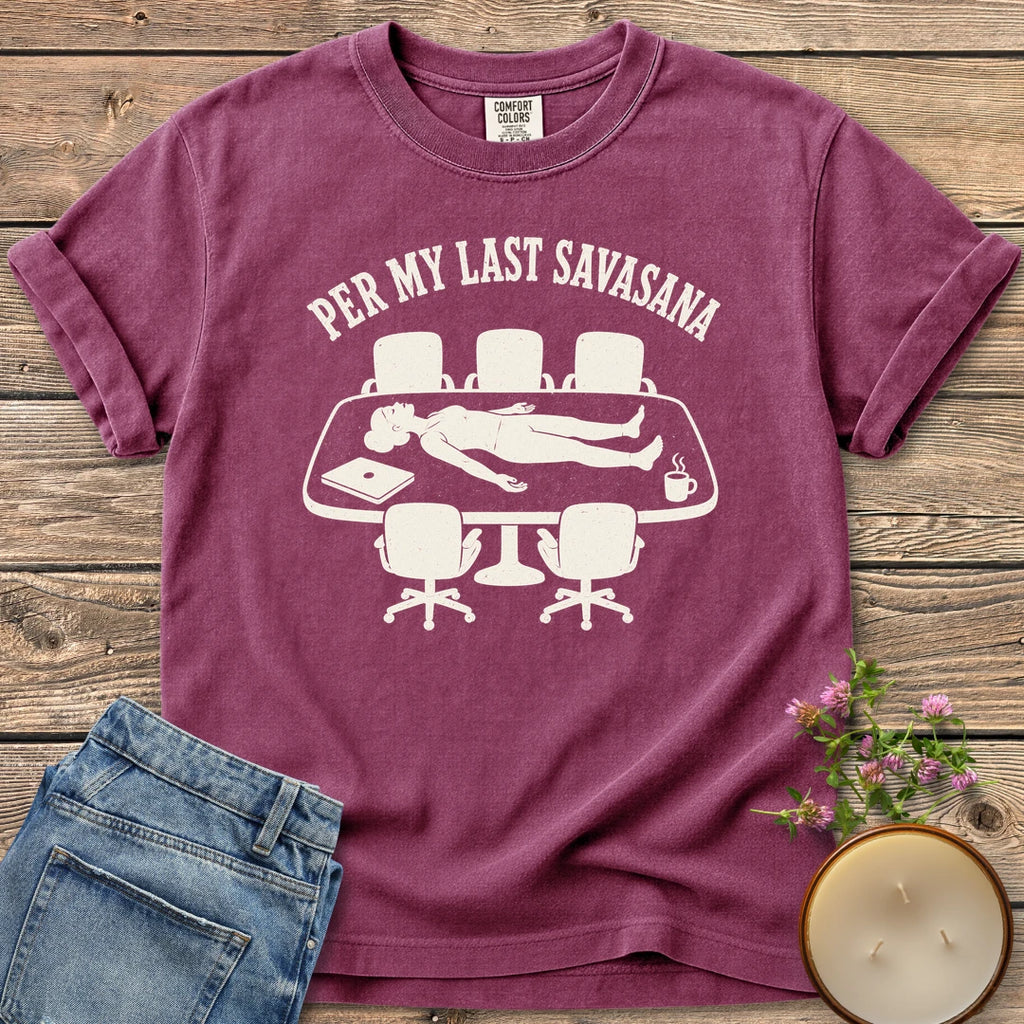 Per My Last Savasana t-shirt, a person lying flat on a conference table under Per My Last Savasana, on a Berry Comfort Colors tee