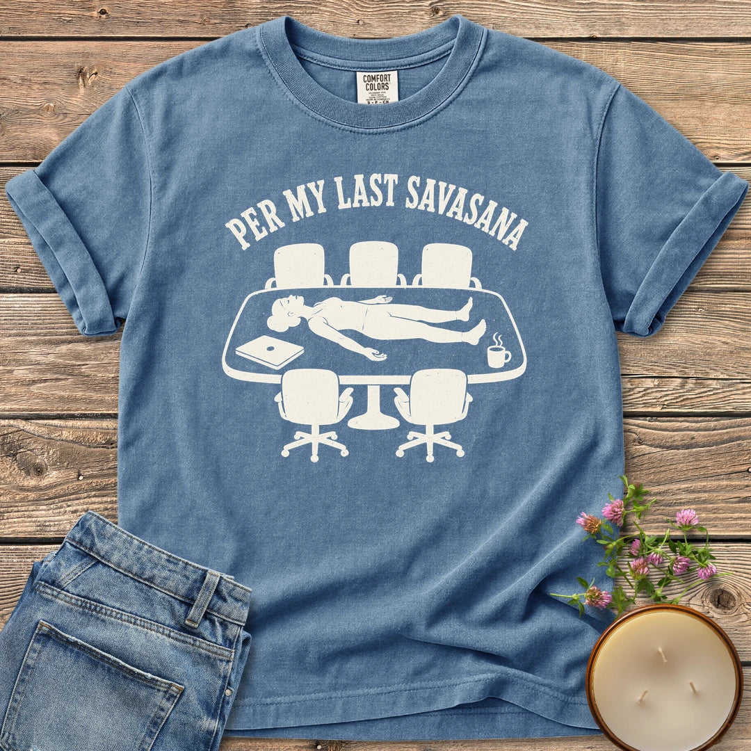 Per My Last Savasana t-shirt, a person lying flat on a conference table under Per My Last Savasana, on a Blue Jean Comfort Colors tee